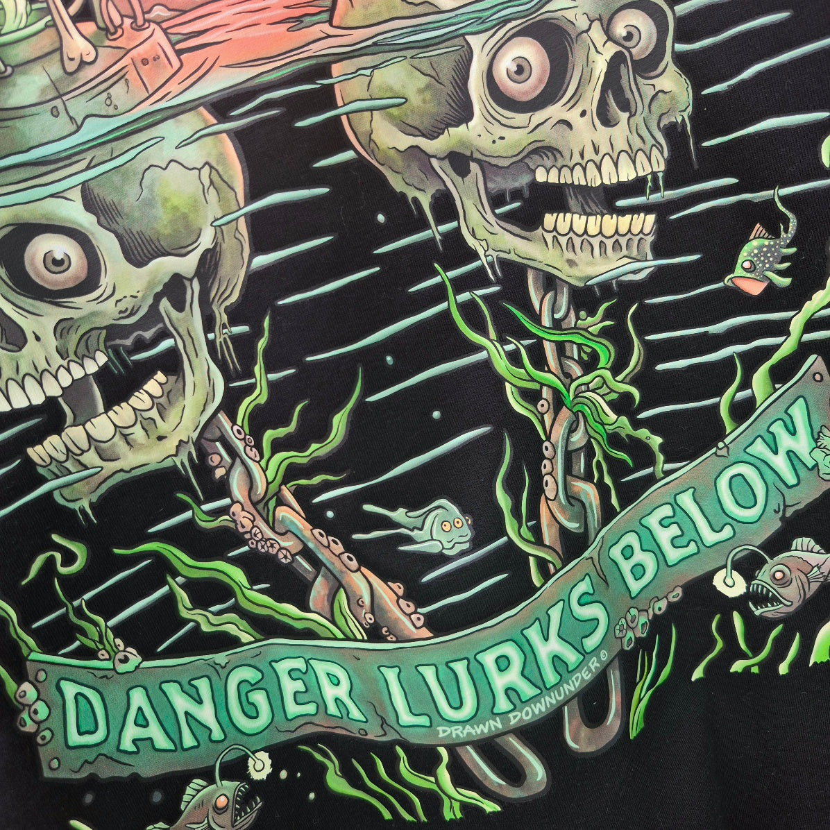 Close up detail of Bad Buoys back print - Danger Lurks Below banner text and chain detail on black t-shirt - Drawn Downunder hand drawn art